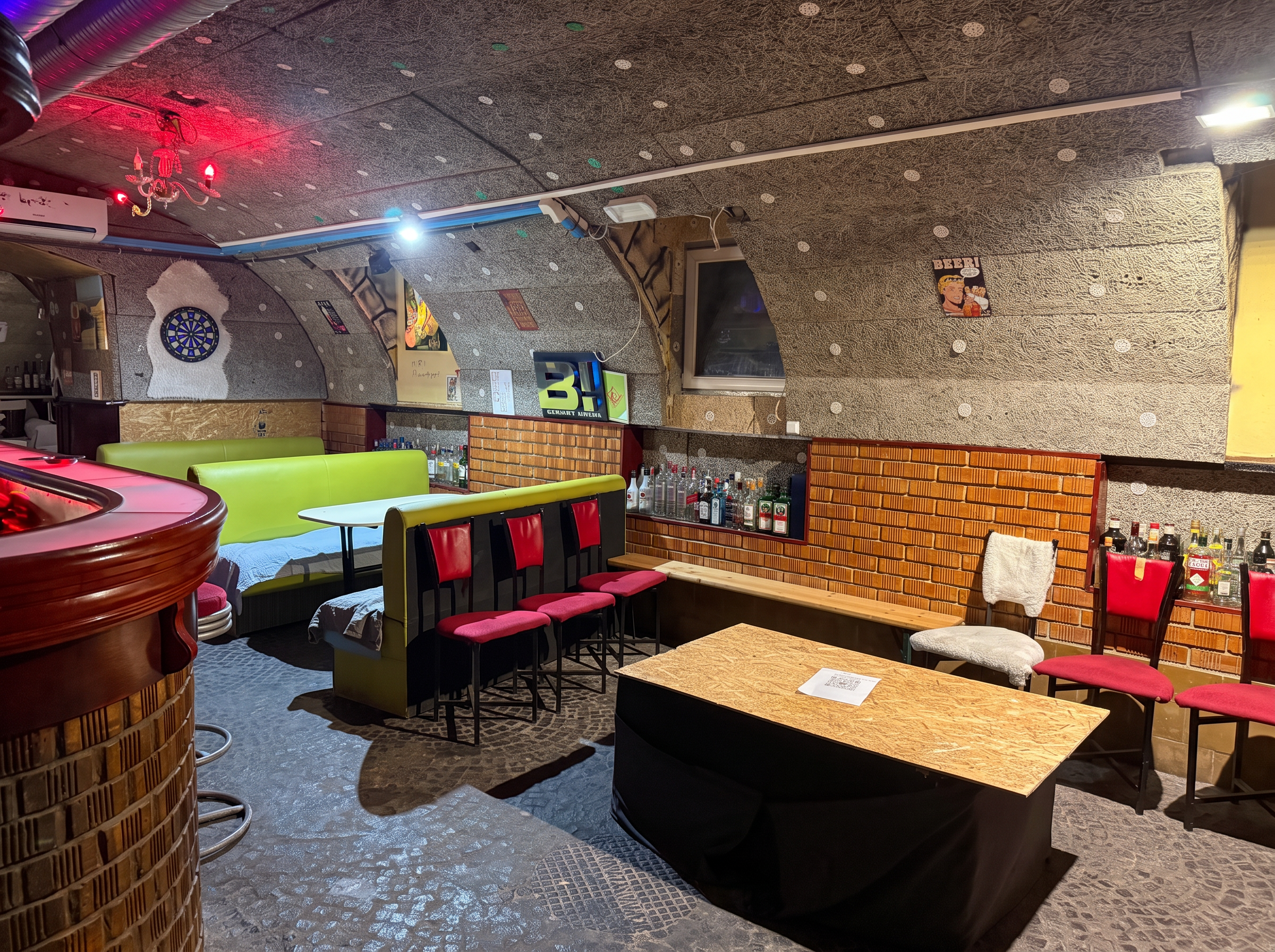Private bar lounge with corner sofa, brick wall, darts and stocked shelves